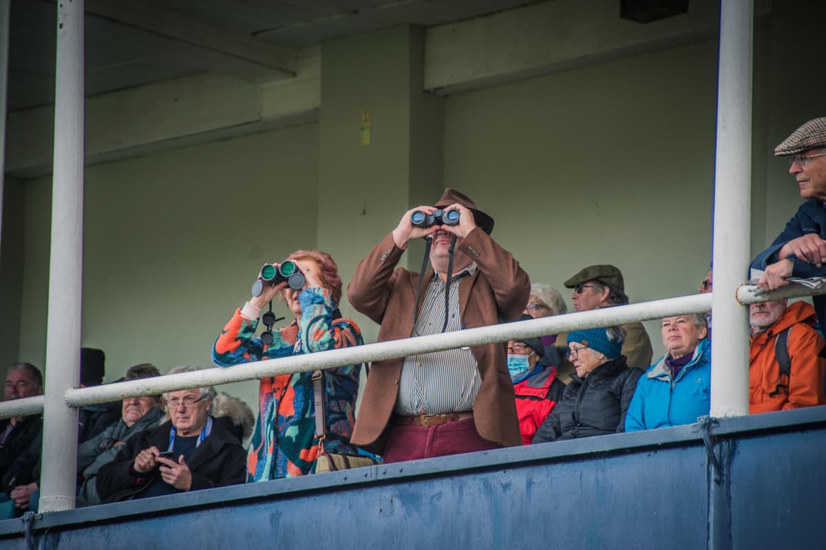 Racegoers watching through binoculars